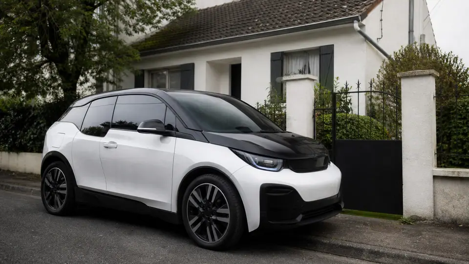 Petite voiture électrique garée devant une maison résidentielle française